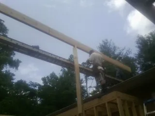 Carpenter setting a ridge beam over a new addition frame — Ice Dam Removal by Roofing Brothers in Hogansville
