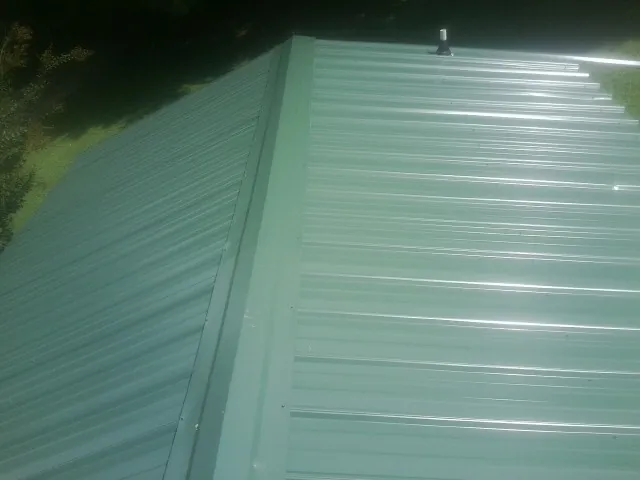 New green metal panels meeting at the ridge of a roof — Flat Roof Repair work by our crew in Hogansville