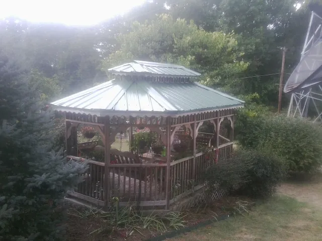 Green metal roof on a backyard gazebo surrounded by garden beds in Hogansville