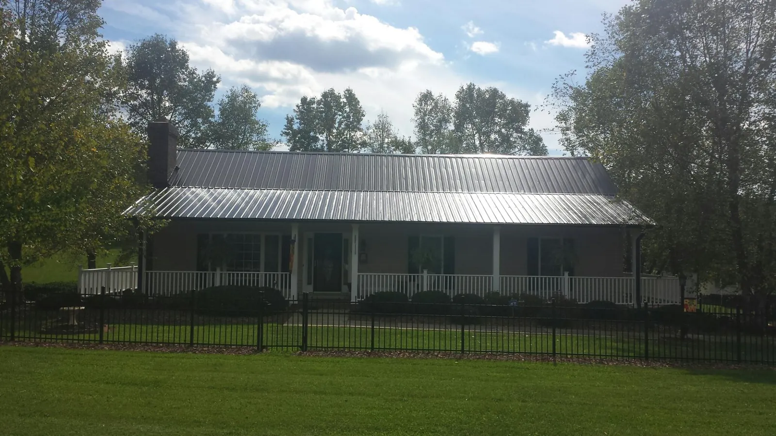 Gray metal roof on a brick ranch with a full width front porch — Gutter Guard Installation work by our crew in Hogansville
