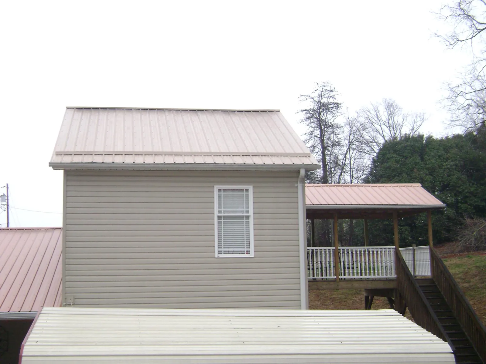 Tan metal roofs on a two story addition and attached porch, from a Roof Replacement job in Hogansville